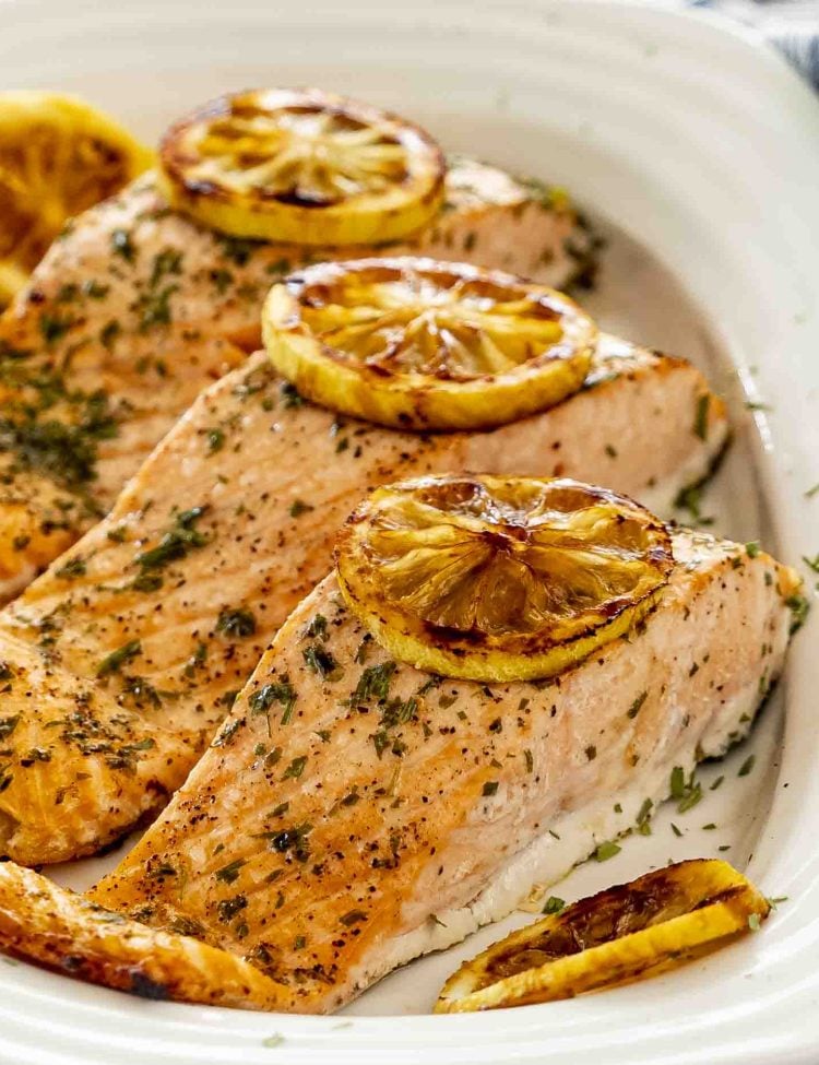 baked salmon with lemon slices on a white platter.