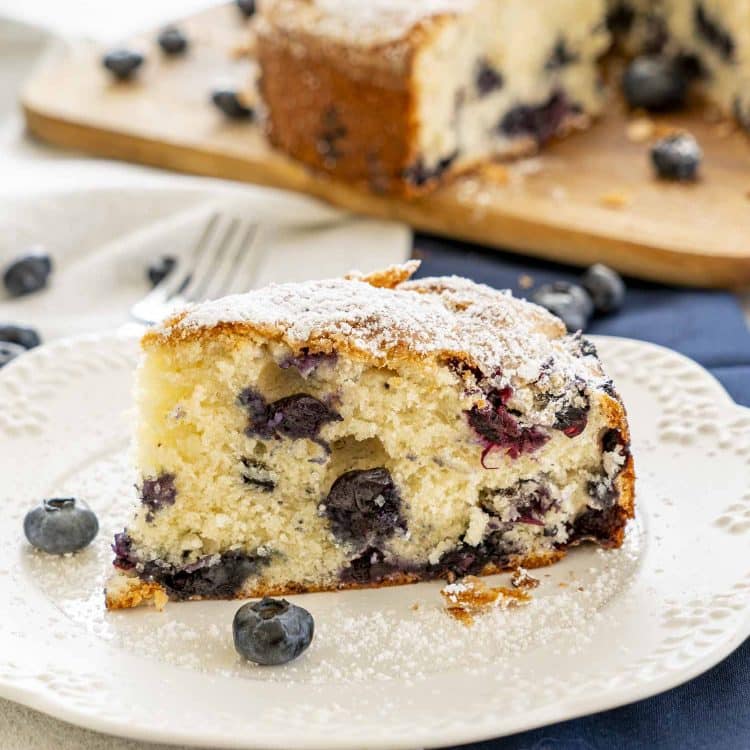 a slice of old fashioned blueberry cake on a white plate.