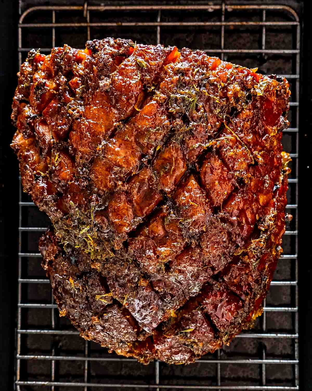 bourbon glazed baked ham on a roasting pan with a rack fresh out of the oven.