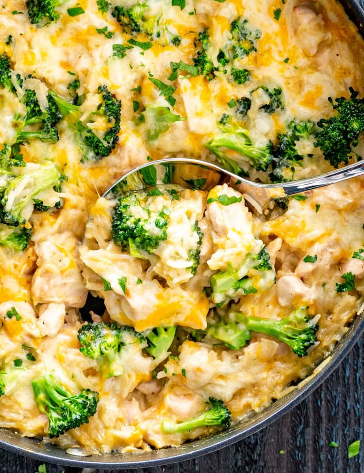 a serving spoon inside a skillet with chicken broccoli rice casserole.