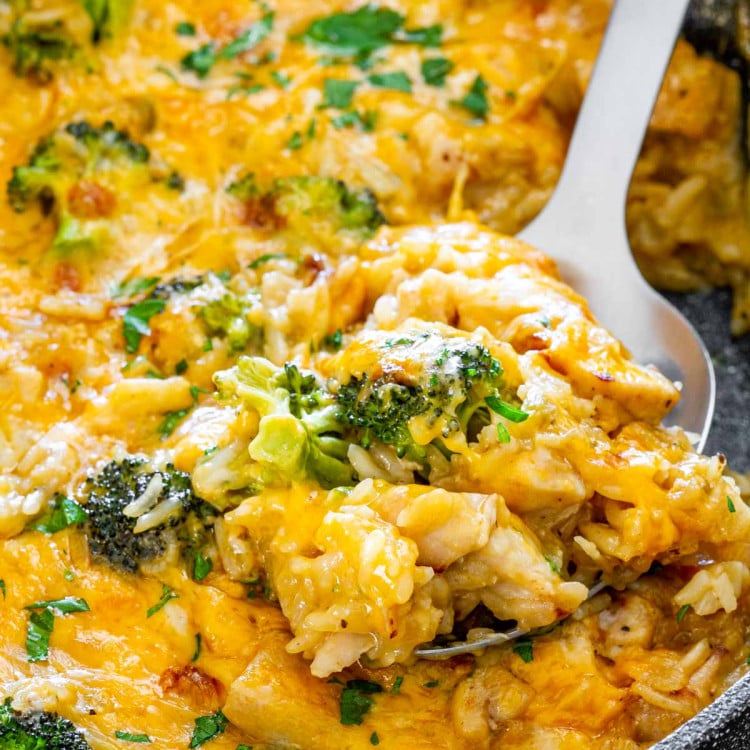 a serving spoon inside a skillet with chicken broccoli rice casserole.