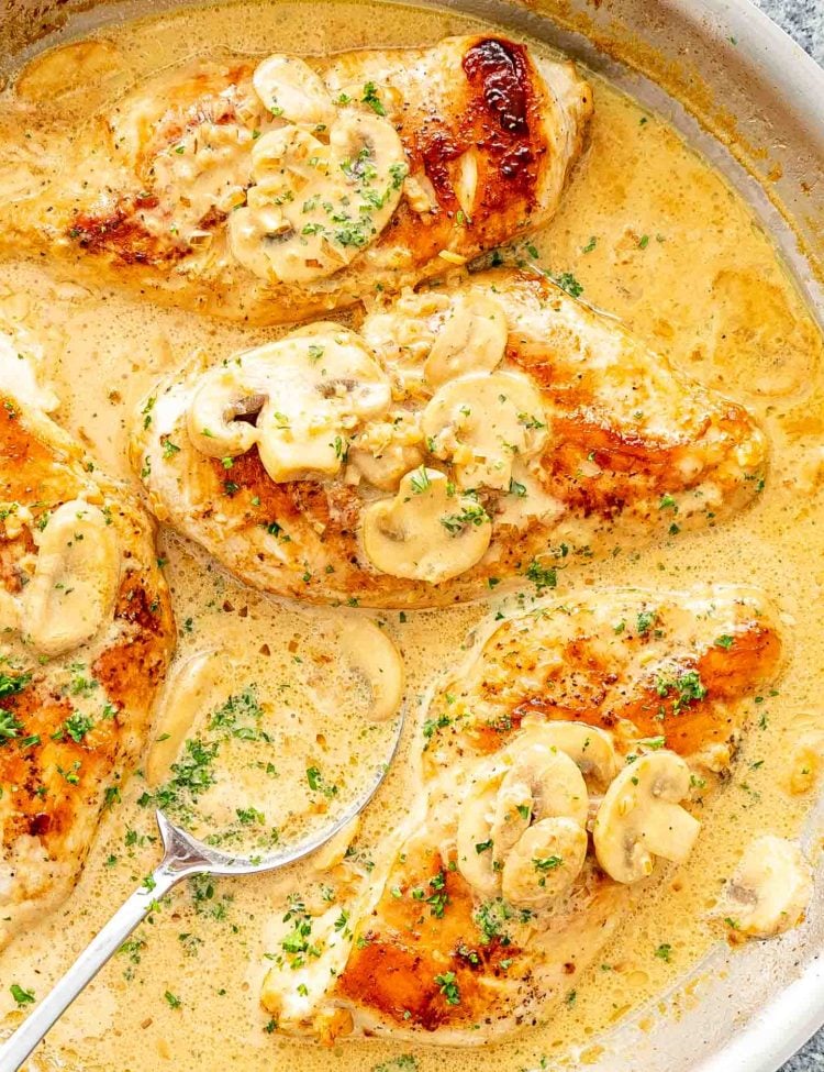 Golden Chicken Diane with mushrooms in a creamy sauce, sprinkled with parsley in a skillet.