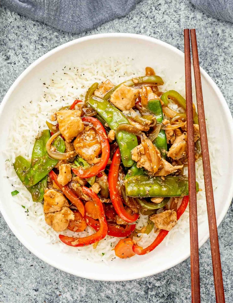 chop suey over a bed of rice in a white plate.