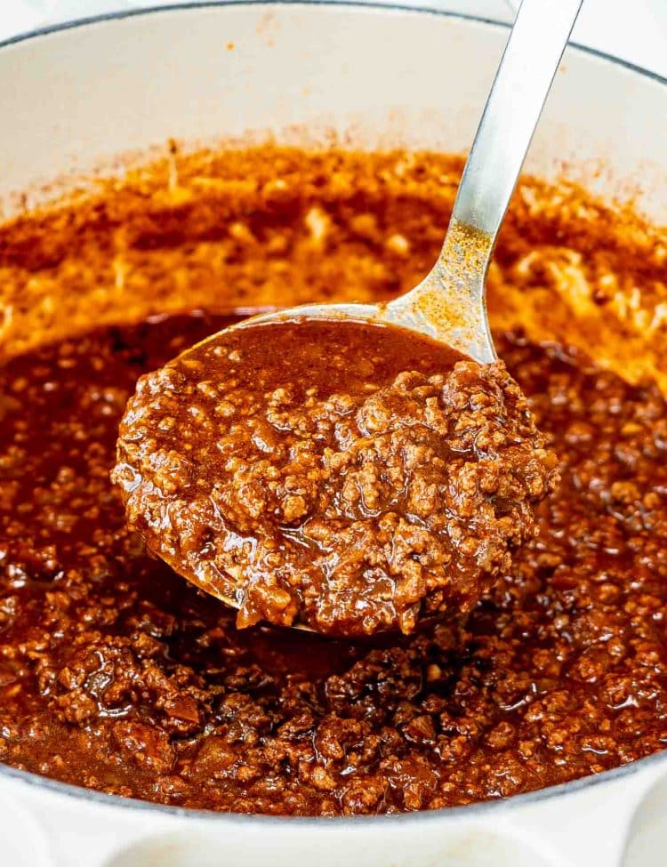 a Dutch oven with freshly made cincinnati chili and a ladle inside.