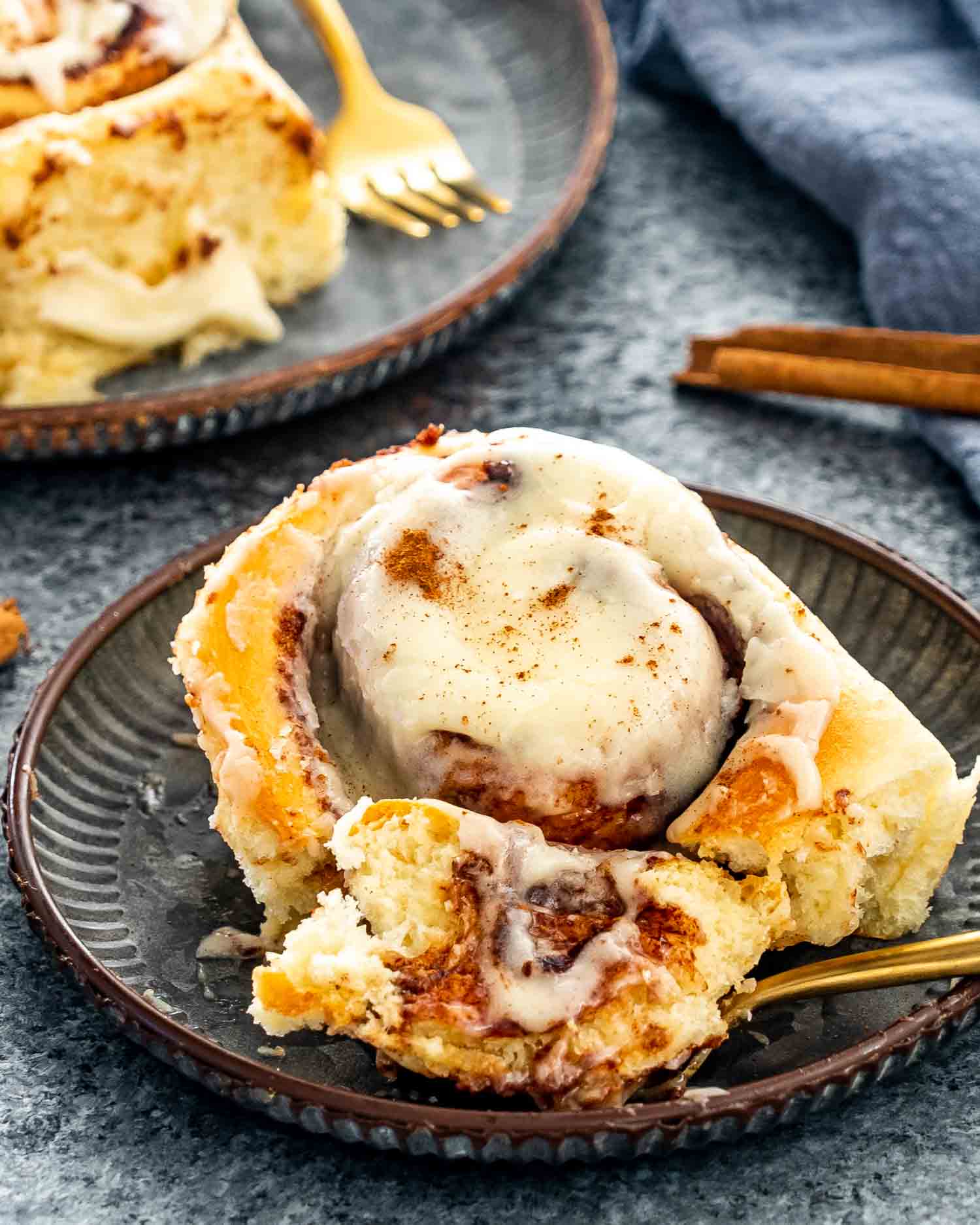 a cinnabon cinnamon roll on a metal plate.