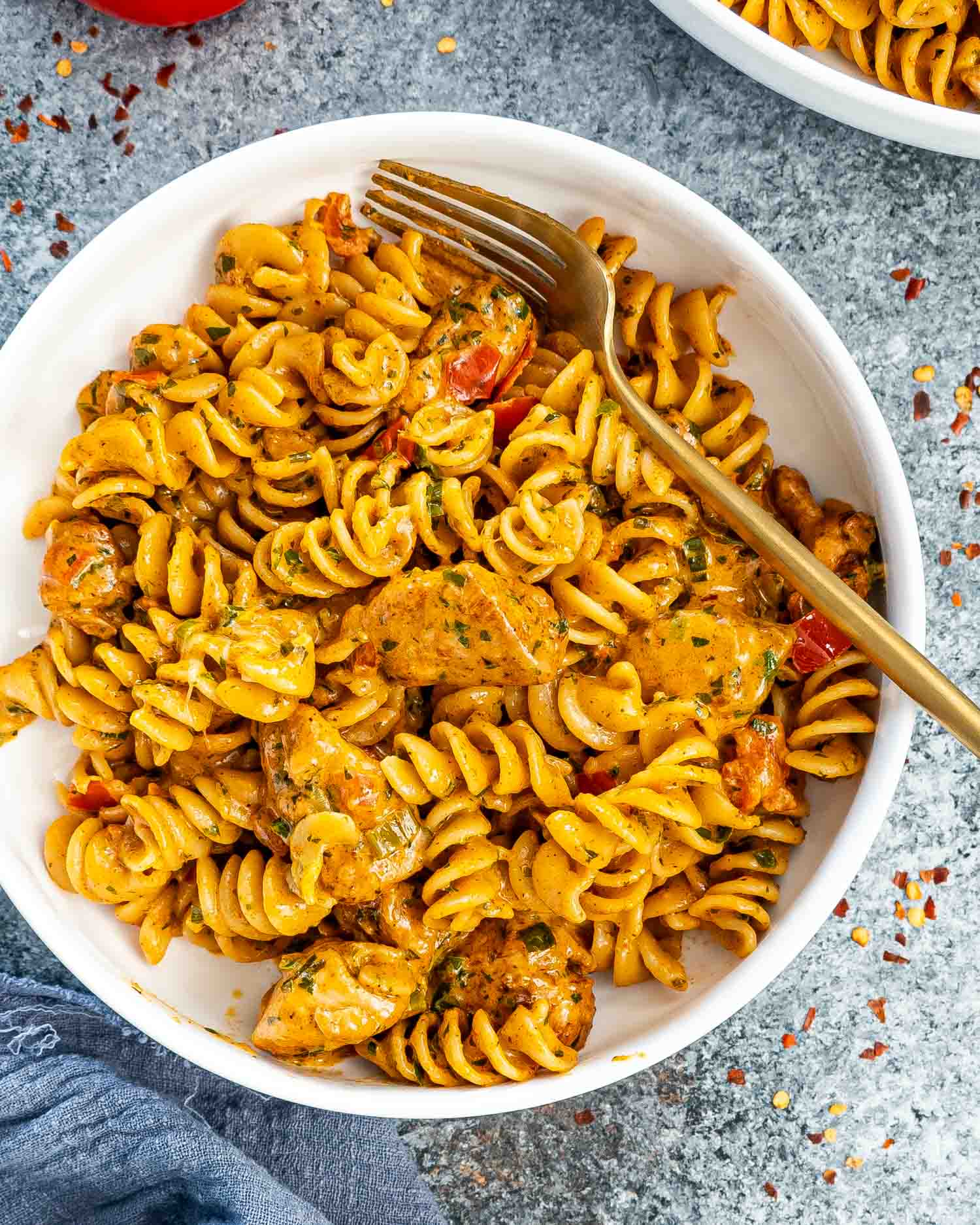 creamy tomato chicken pasta in a white bowl with a fork in it.