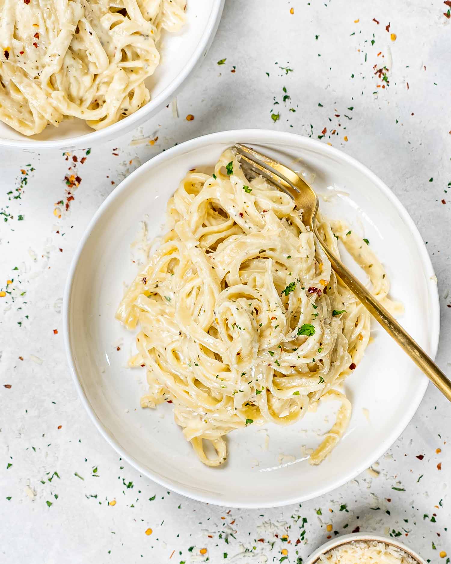 a serving of fettuccine alfredo in a white bowl with a golden fork.