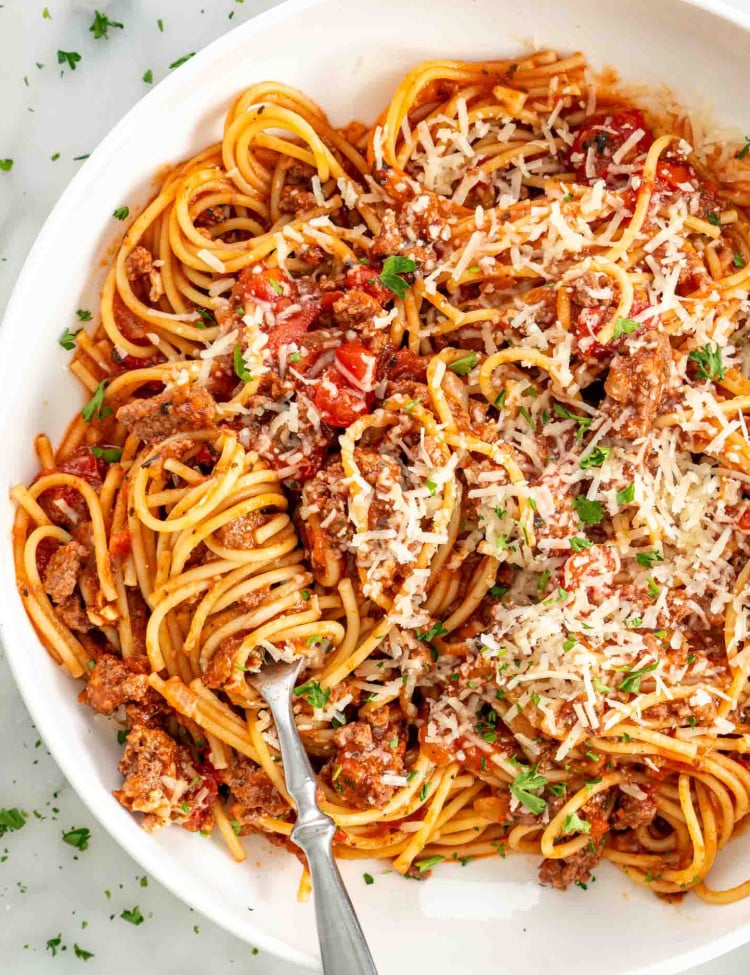 overhead shot of a fork with spaghetti twirled around it in a plate full of spaghetti.