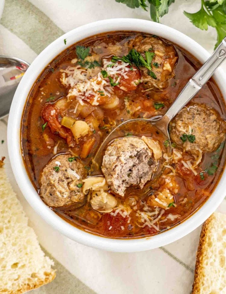 a spoon taking a scoop of italian meatball soup from a bowl