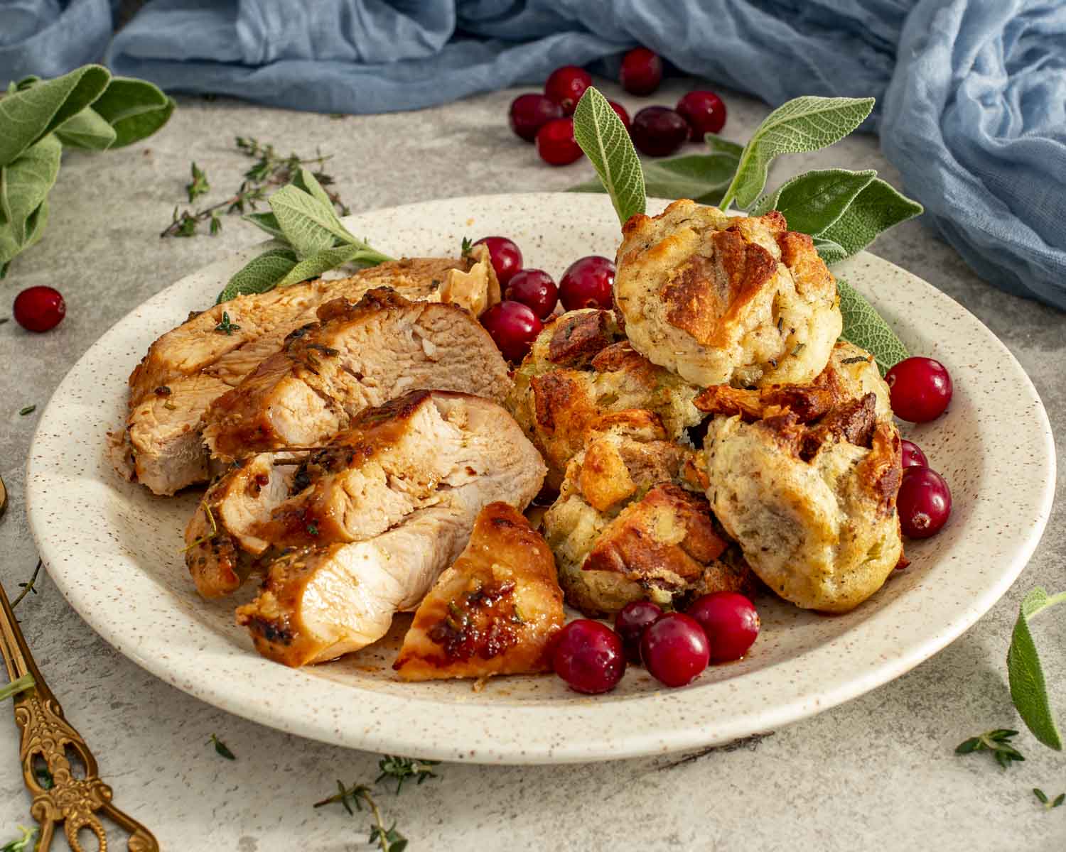 Sliced Maple Dijon Glazed Turkey Breast served with golden stuffing balls, fresh cranberries, and herbs on a festive plate.