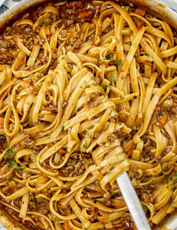freshly made one pot beef ragu pasta in a skillet garnished with a bit of parsley.
