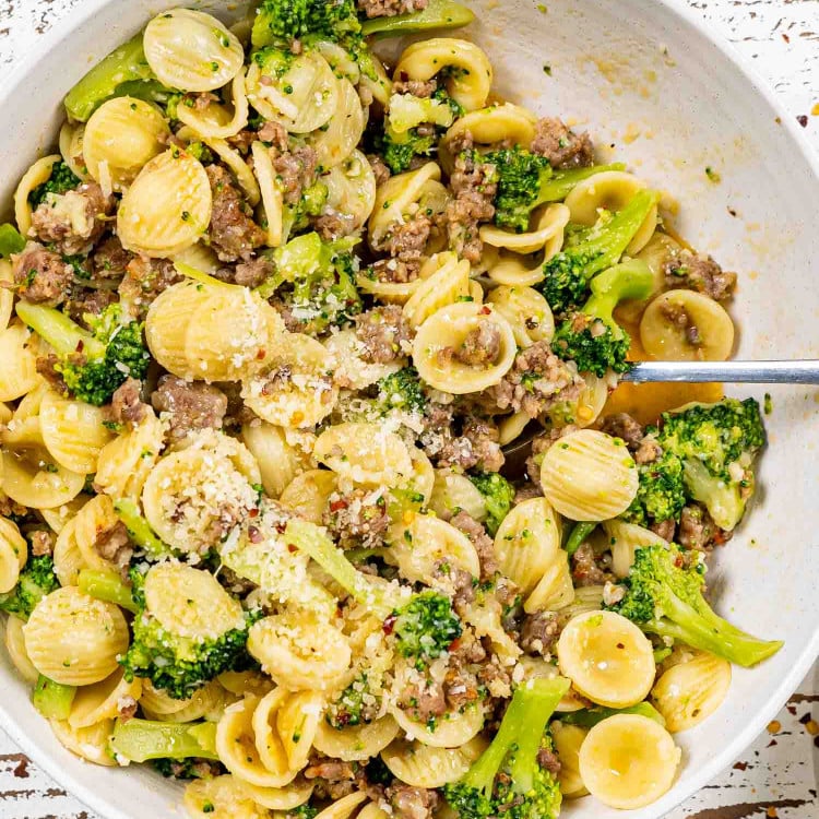 orecchiette with sausage and broccoli in a white serving bowl.