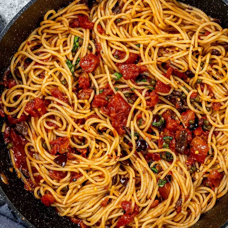 freshly made pasta puttanesca in a blue skillet.