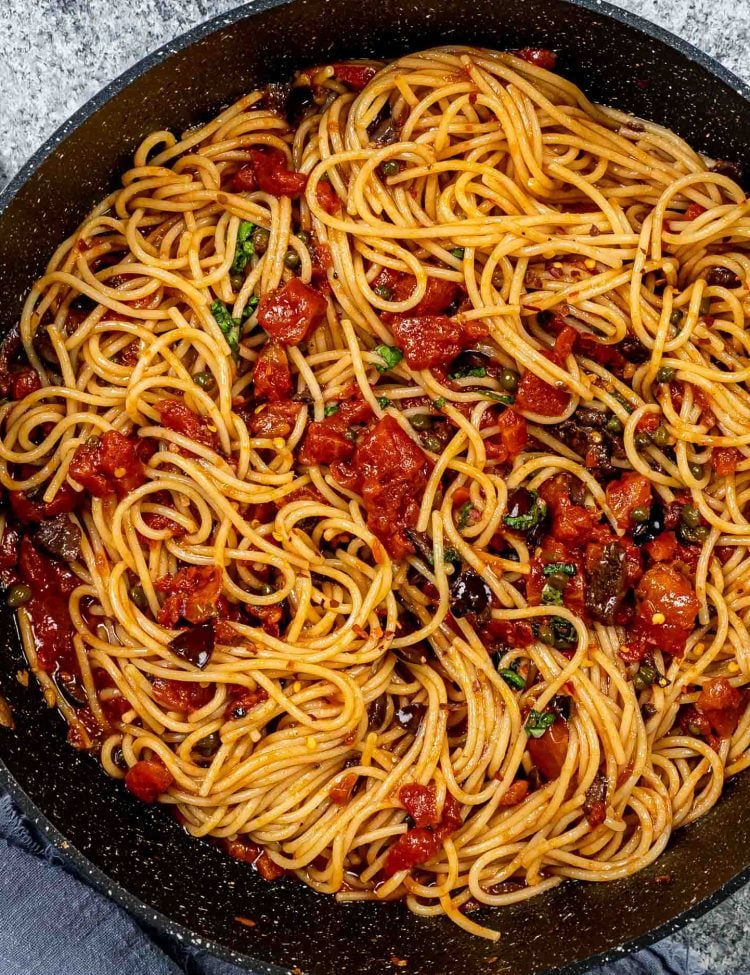 freshly made pasta puttanesca in a blue skillet.