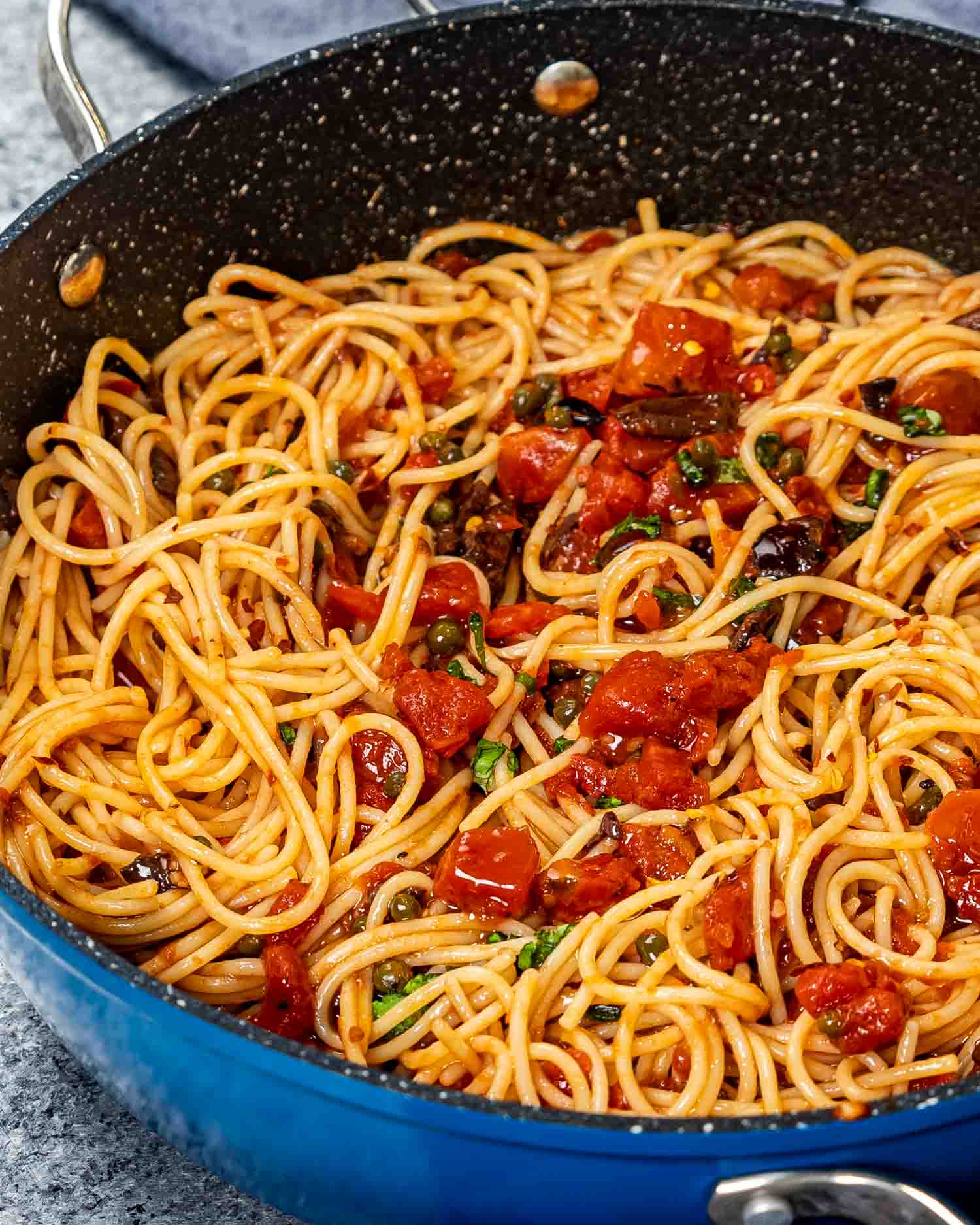 freshly made pasta puttanesca in a blue skillet.
