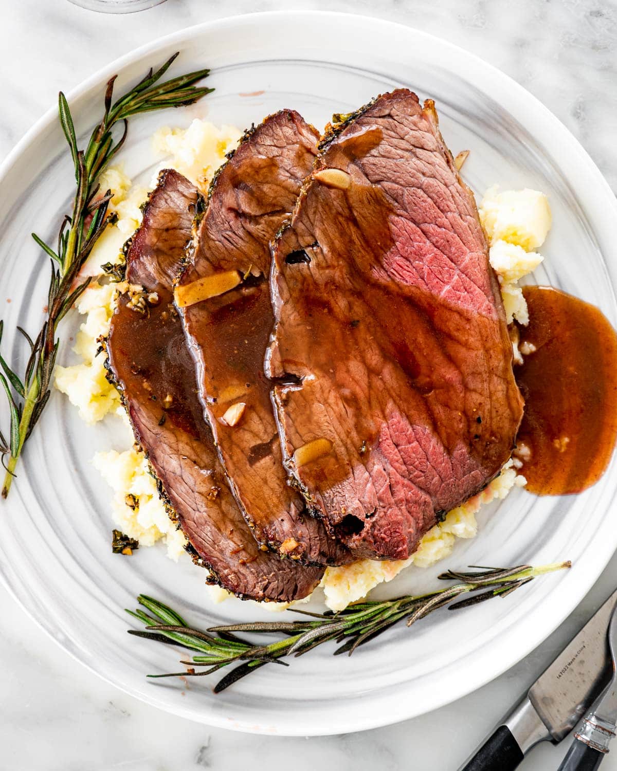 overhead shot of 3 slices of roast beef over a bed of mashed potatoes topped with gravy