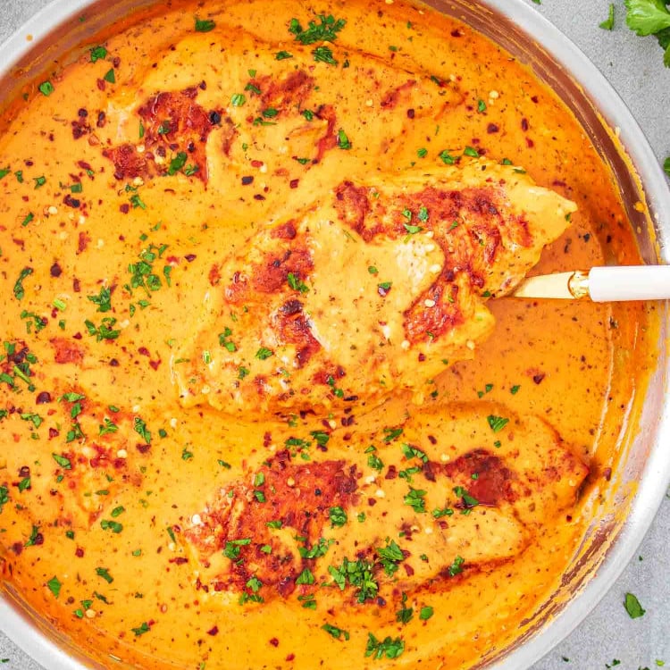 roasted red pepper chicken in a skillet garnished with parsley.