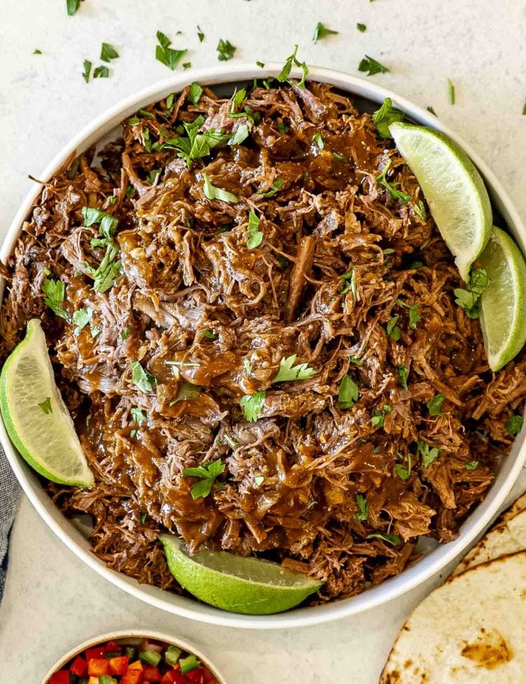 Juicy slow cooked pulled beef topped with rich BBQ sauce and fresh parsley, served with lime wedges.