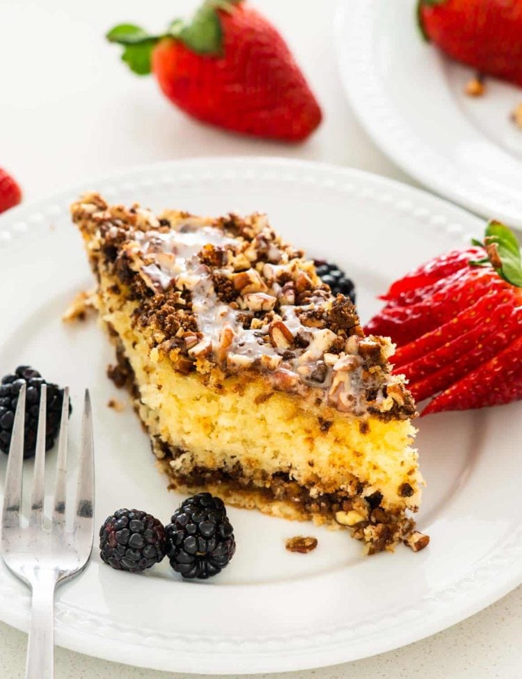 a slice of sour cream coffee cake on a white plate with a strawberry.
