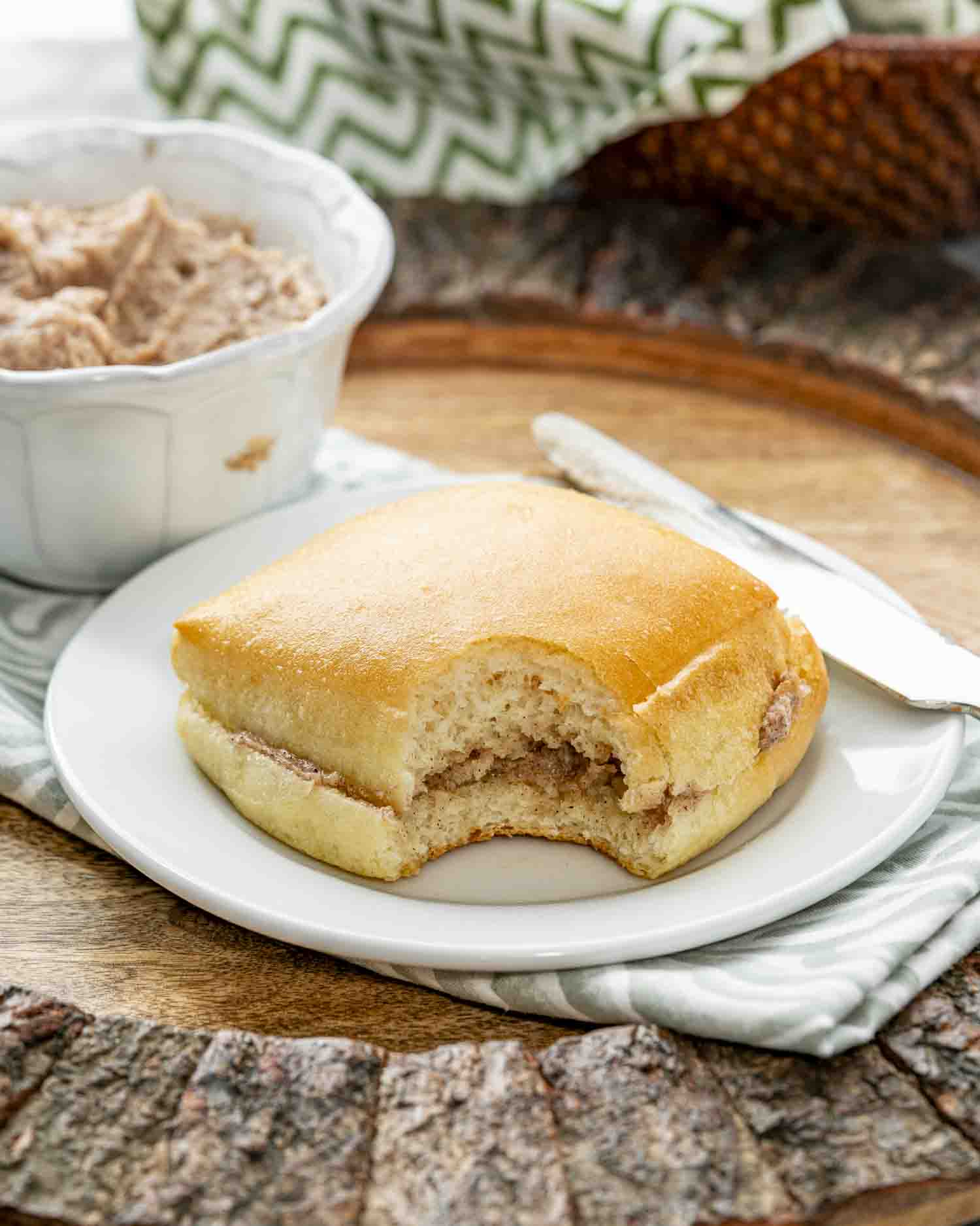 a texas roadhouse roll with honey cinnamon butter on a white plate.