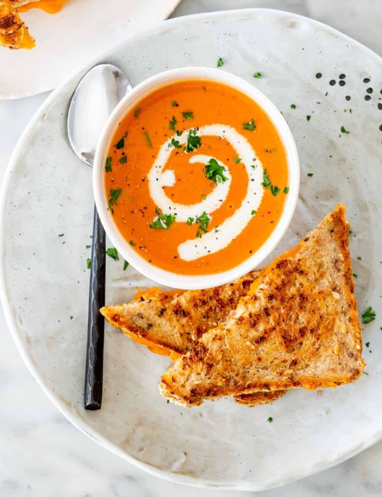 tomato bisque in a soup bowl with a grilled cheese sandwich