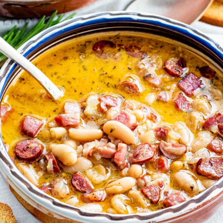 sideview shot of a tuscan bean soup in a clay bowl with a spoon inside