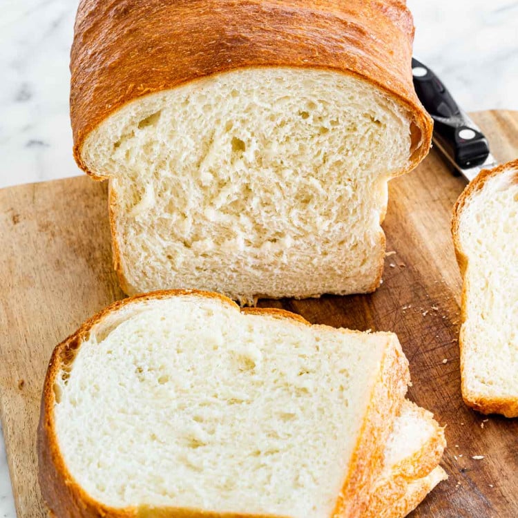 a loaf of white bread sliced on a cutting board